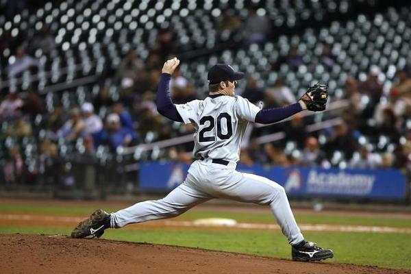 Pitcher on the mound, legs stretched out, arm wound back, ready to let the ball fly.