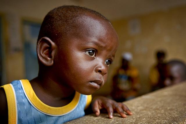 A very young black child looking forward pensively.