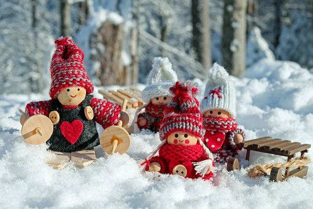 Wooden doll figures bundled up in a snowy scene, with sled and scarves and woolen hats.