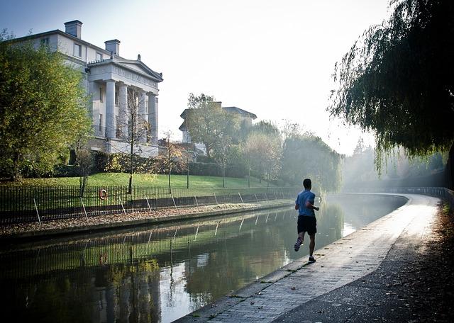 A man running away from us along a stone pathway along a river.