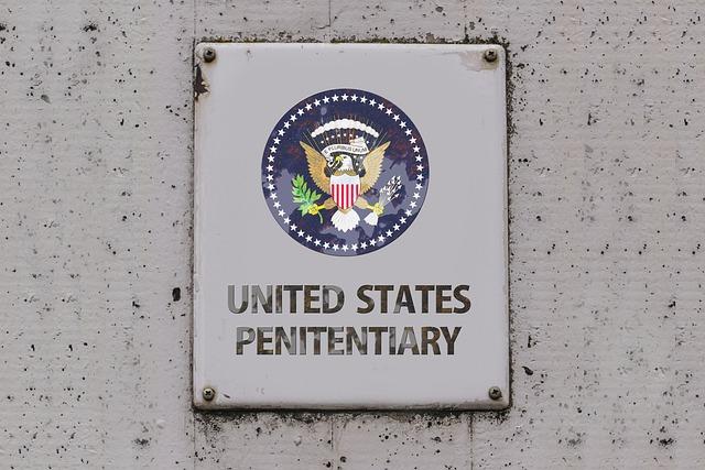 A white sign on a white concrete wall that reads, United States Penitentiary.