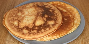 Two large pancakes on a grey plate waiting for butter and syrup.