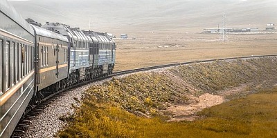 Looking along the side of train enroute across a bleak landscape.